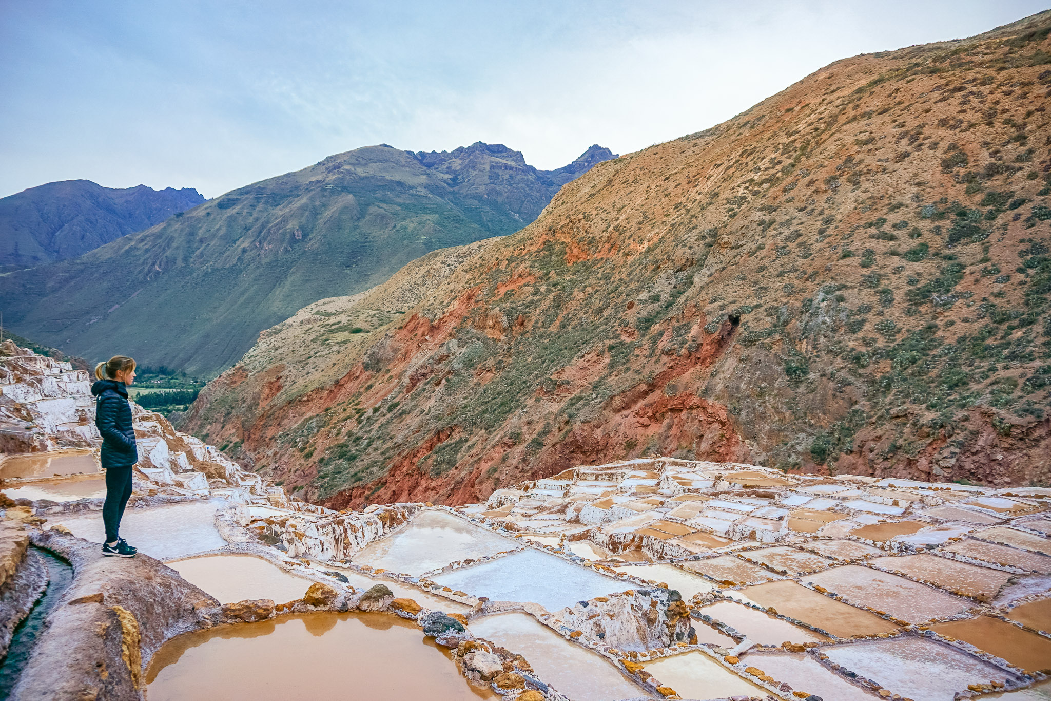 a woman on a terrace, gazing at a the sacred valley salt mines.